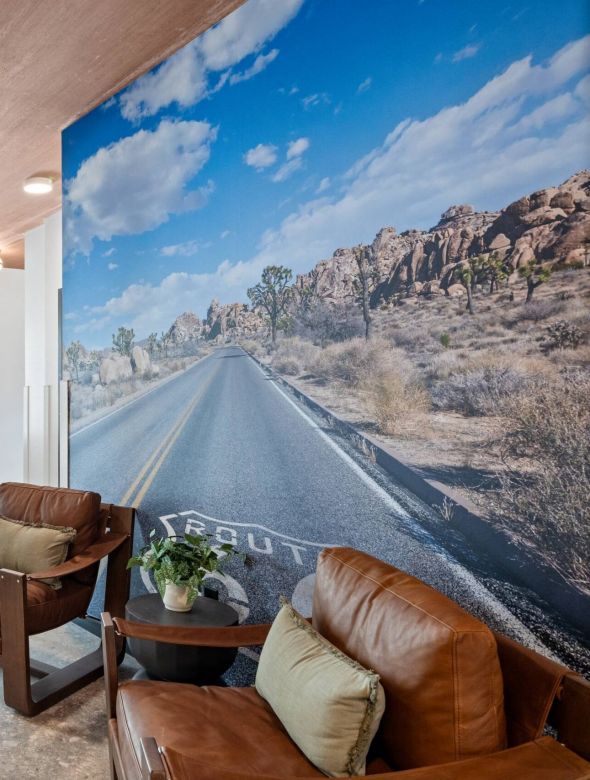 Sierra on 66 Small lobby with two leather chairs, a large desert road mural, and glass doors leading outside.