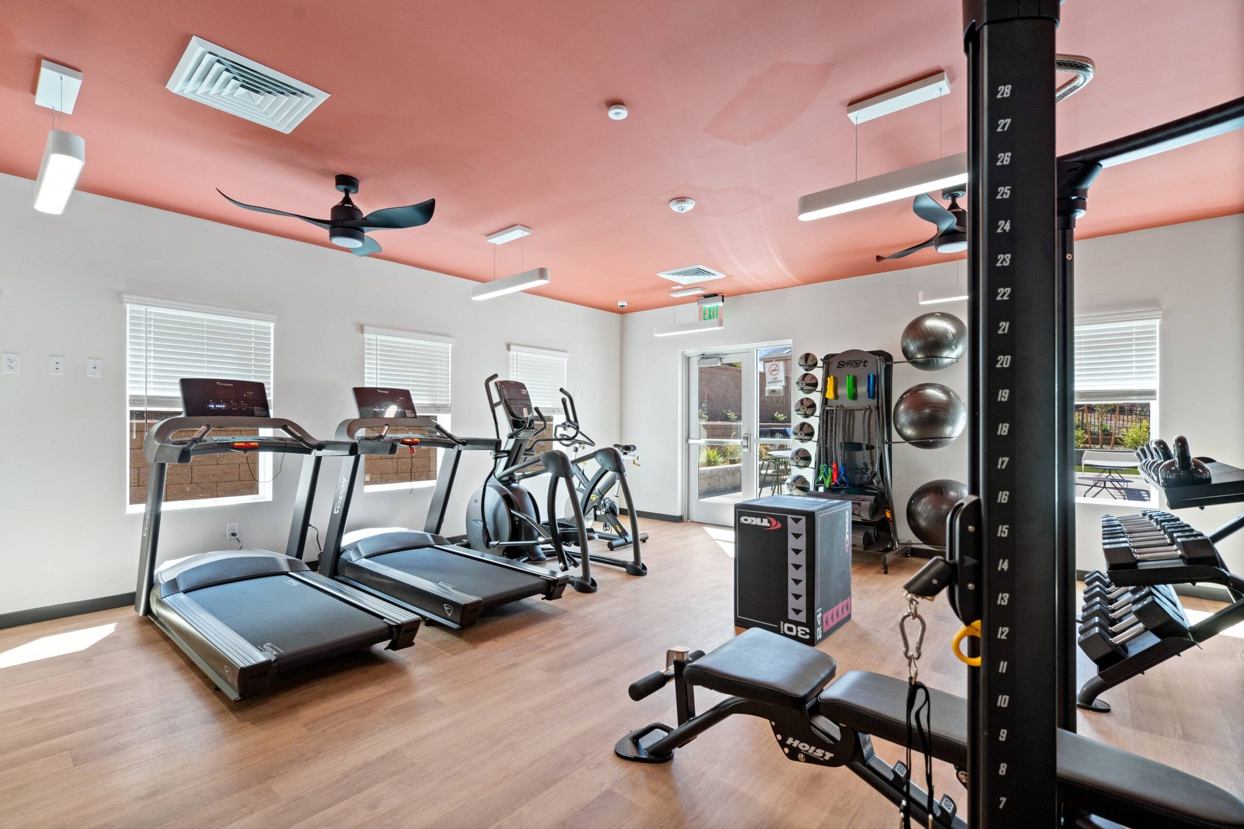 Sierra on 66 Small gym room with treadmills, elliptical, weight rack, exercise balls, and bright windows.
