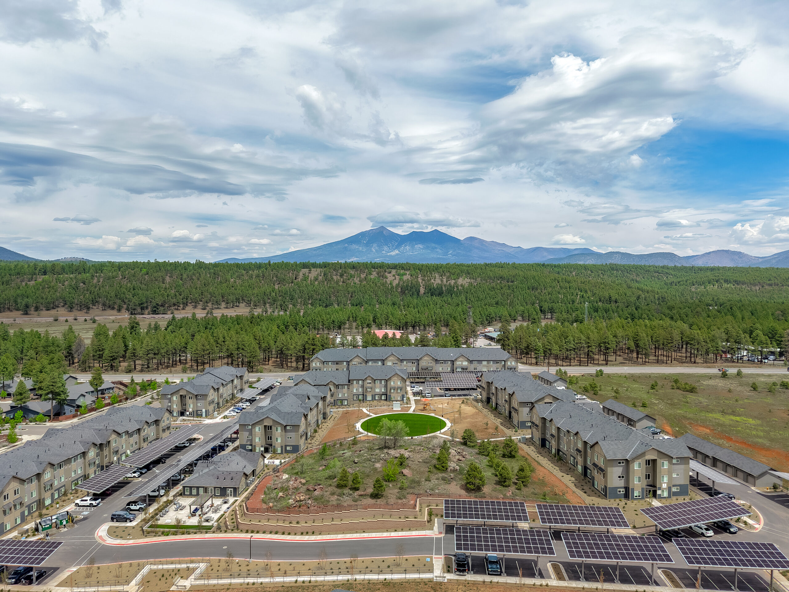 Sierra on 66 Aerial view of an apartment complex surrounded by trees with mountains in the background under a cloudy sky.