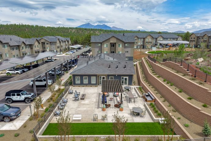 Sierra on 66 Apartment complex courtyard with outdoor seating, grill area, and mountain views in the background.